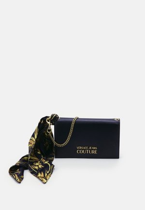 Czarna kopertówka Versace Jeans Couture z złotym łańcuszkiem i czarno-złotym wzorzystym materiałem związanym po jednej stronie.