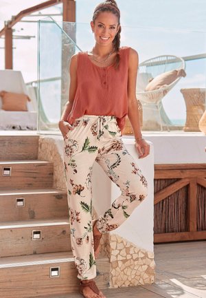Canottiera di corallo leggera con dettagli bottoni abbinata a pantaloni crema con motivo floreale, dotati di una vita elastica e tasche.
