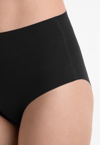 Höga svarta underkläder med slät tyg, elastisk textur och rena sömmar, med en enkel design utan mönster eller dekorationer.