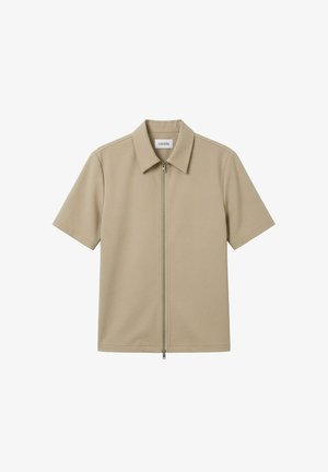 Beige kortermet skjorte med spiss krage og sølvfarget frontglidelås, vist flatt mot en hvit bakgrunn.