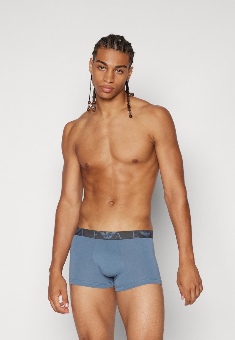 Boxer shorts de algodón azul con una cinturilla elástica negra que presenta un logotipo. La tela tiene una textura suave y un diseño ajustado.