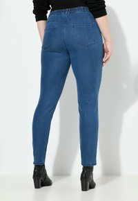 Siniset farkut, joissa on muotoiltu malli, joustava vyötärö ja kaksi takataskua. Yhdistetty mustiin nilkkureihin. Sujuva rakenne.