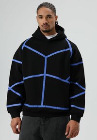Zwarte hoodie met blauwe geometrische lijnen. Voorzien van een grote kangoeroezak, verstelbare capuchon en geribbelde boorden en zoom. Gemaakt van zachte stof.