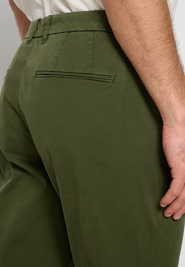 Pantaloni in cotone verde a vestibilità slim, con una tasca posteriore e dettagli di cucitura discreti. Texture liscia e design strutturato.