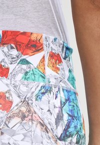 Multicolored leggings featuring a diamond pattern in orange, green, and blue, with a smooth texture and elastic waistband.