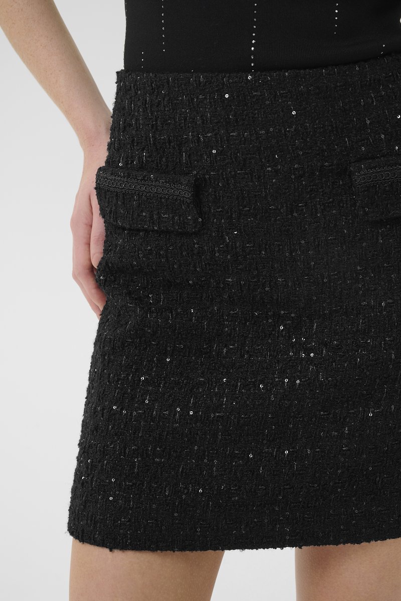 Schwarzer Tweed-Minirock mit strukturiertem Oberflächendesign und Pailletten, zwei vorderen Taschen und einer figurnahen Silhouette.