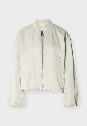 Ανοιχτό μπεζ μπουφάν μπόμβερ με φερμουάρ μπροστά, ριμπ γιακά, μακριά μανίκια και δύο πλαϊνές τσέπες, τοποθετημένο επίπεδα σε λευκό φόντο.