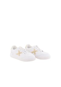Zapatillas blancas de cuero con textura suave, que presentan un diseño de cruz dorada en los laterales y una suela de goma blanca.