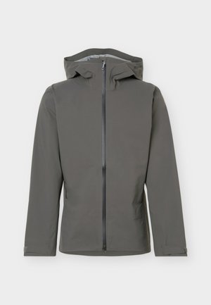 Giacca grigia con cappuccio, cerniera frontale e cinturini regolabili ai polsi, progettata per la protezione dagli agenti atmosferici esterni.