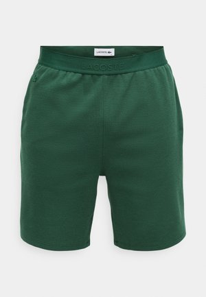 Pantalones cortos verdes hechos de tejido texturizado, con una cintura elástica que presenta un logo en relieve y dos costuras laterales.