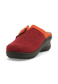 Zoccolo in feltro rosso e arancione con punta arrotondata, suola a cuneo bassa e un bottone decorativo sul lato superiore. Il materiale testurizzato sembra morbido.