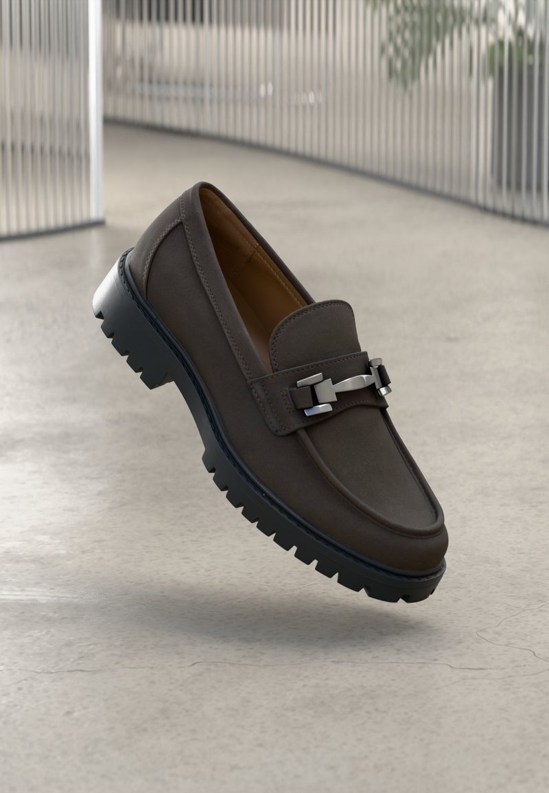 Hnedá kožená mokasína s hladkým povrchom, striebornými kovovými detailmi, flexibilnou gumovou podrážkou s vzorom a klasickým nazúvacím dizajnom.