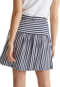 Jupe patineuse à rayures bleu marine et blanc, avec une taille élastique et un design plissé. Fabriquée en tissu léger, adaptée à un usage décontracté.