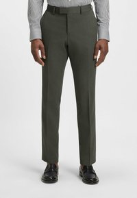 Dark green, textured dress pants with a slim fit, flat front, and side pockets, paired with black leather loafers and a striped shirt.