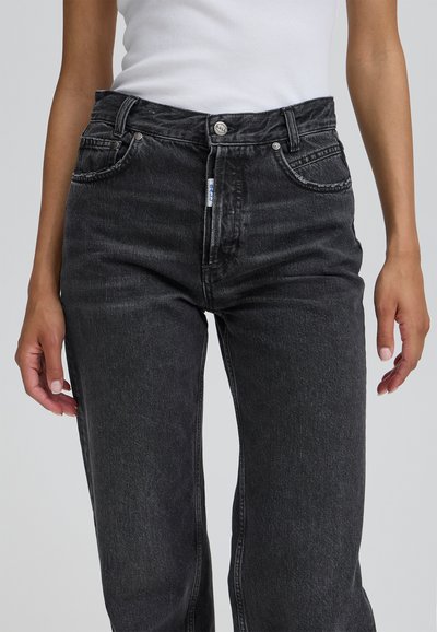 Crne traperice s visokim strukom, s prednjim džepovima, metalnim dugmetom za zatvaranje i ravnim krojem. Suptilna tekstura i izblijedjelo stanje.