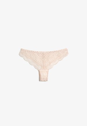 String de femme en dentelle rose clair avec motifs floraux et géométriques ainsi que des bords festonnés, posé à plat sur un fond blanc.