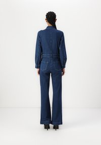 Denim jumpsuit met lange mouwen, een cinched taille en wijde broekspijpen. Heeft twee achterzakken en een gladde, donkerblauwe textuur.