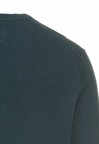 Dunkelgrüner, gestrickter Pullover mit texturierter Oberfläche. Verfügt über einen Rundhalsausschnitt und markante Nähte an den Schultern und am Halsauschnitt.