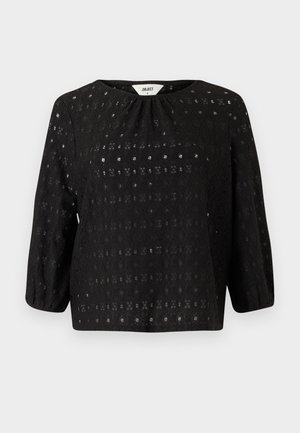 Haut noir en dentelle avec des manches trois quarts et un col rond. Présente un motif texturé avec une coupe loose. Associé à un jean bleu clair.