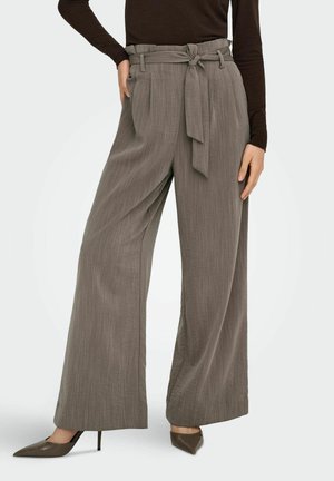 Pantalon large gris avec une taille ceinturée, tissu texturé et rayures verticales. Assorti à des escarpins à bout pointu pour le contraste.