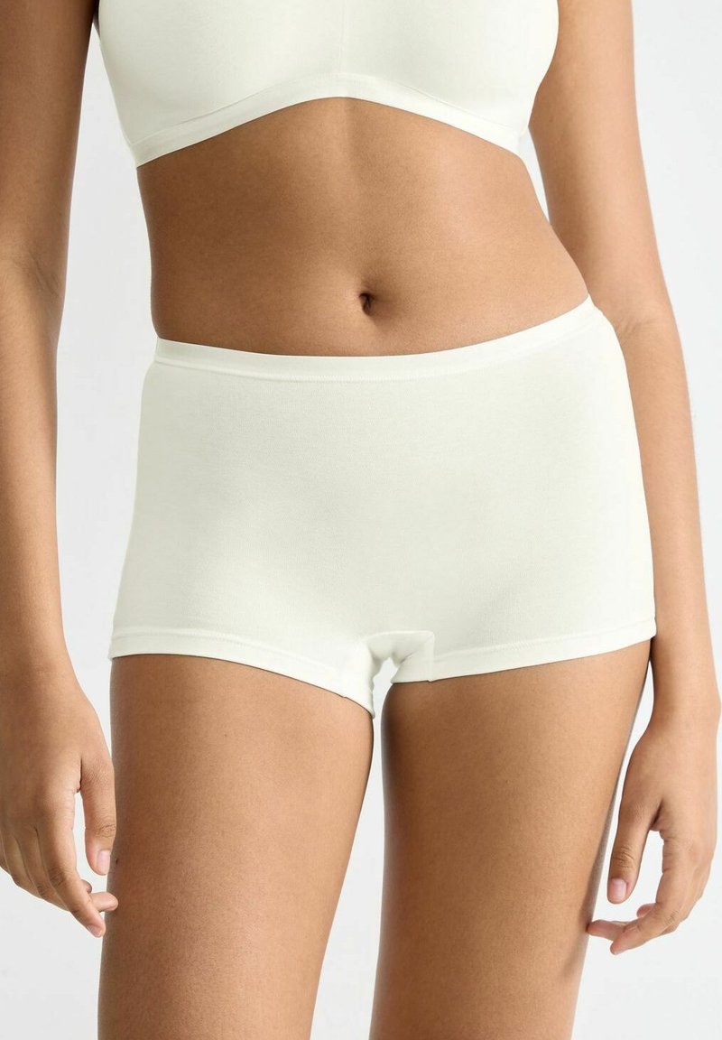 Light cream-colored fitted shorts made of soft fabric, featuring an elastic waistband and a seamless design for comfort.