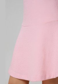 Robe tricotée rose avec un corsage ajusté et une jupe évasée, dotée d'une surface texturée et d'un design sans couture.