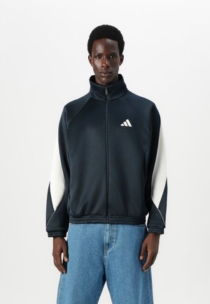 Marinefarbener Reißverschlussjacke mit hohem Kragen, weißen Akzenten an den Ärmeln, elastischem Bund und dem Adidas-Logo auf der linken Brust. Glatte Stofftextur.