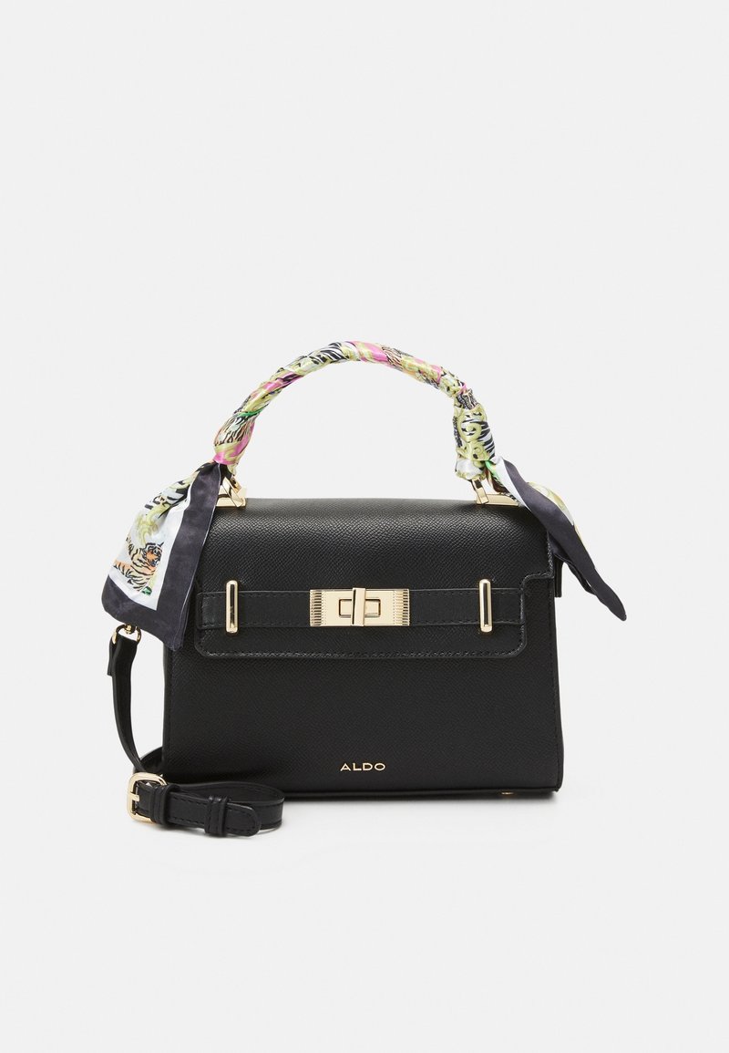 Sac à main Aldo noir avec fermoir doré, foulard fleuri enroulé autour de la poignée supérieure et bandoulière réglable posée devant.