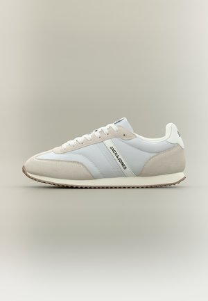 Niski sneaker w kolorze białym i jasnobeżowym z przodu sznurowany, z teksturowaną podeszwą i logo "JACK & JONES" na bocznej ściance.