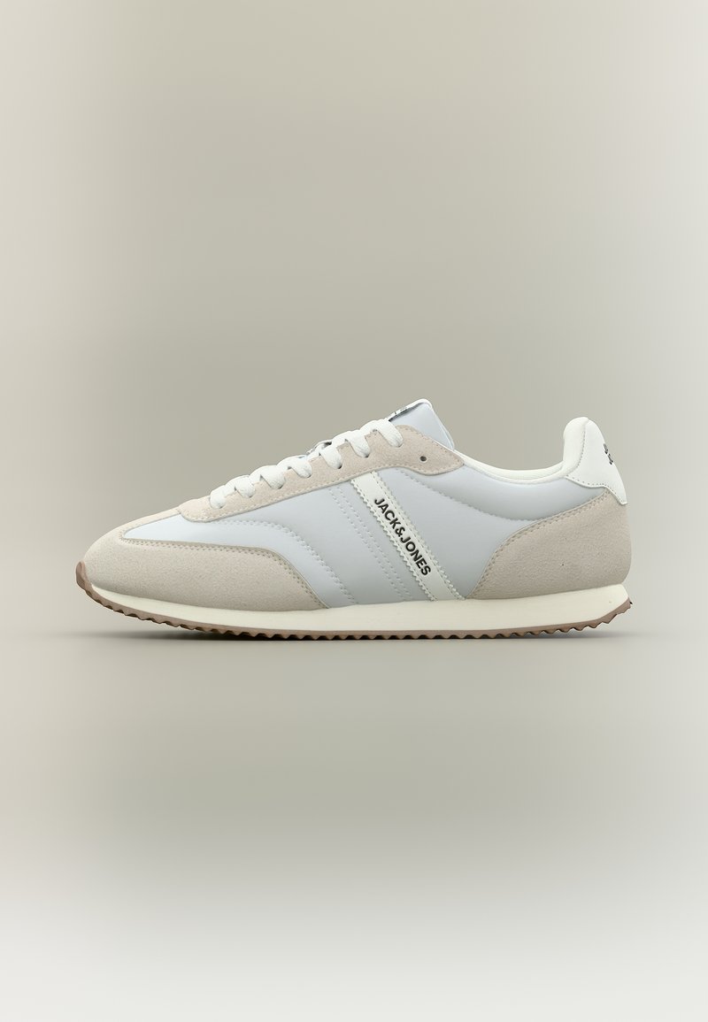 Baskets basses blanches et beige clair avec lacets à l'avant, semelle texturée, et logo "JACK & JONES" sur le panneau latéral.