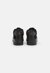 Schwarze Sneakers mit Obermaterial aus Wildleder und Leder, weicher Innenausstattung und goldenen Akzenten. Sie verfügen über ein niedriges Profil und eine strukturierte Gummisohle.