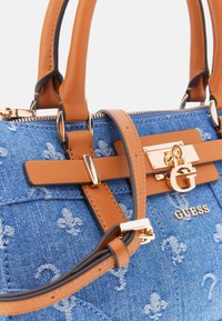 Denim handbag with brown faux leather accents, gold hardware, and floral embroidery. Features dual handles and a detachable strap.