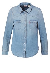Ljust blå denim långärmad skjorta med två bröstfickor, tryckknappar framtill och spetsig krage.