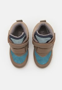 Baskets pour tout-petits marron et bleu en matériau cuir suédé et cuir, avec des bandes Velcro, un col rembourré et une semelle en caoutchouc texturé.