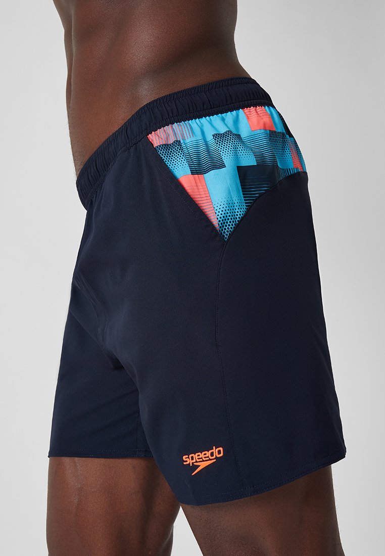 Granatowe kąpielówki z elastycznym pasem. Posiadają kolorowy geometryczny wzór w odcieniach niebieskiego i koralowego po bokach. Logo marki w kolorze pomarańczowym.