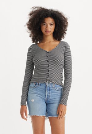 Stripet, svart-hvitt langermet cardigan med V-hals og knappelukk, kombinert med slitte lyseblå denimshorts.