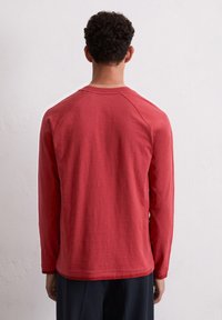 Langarmshirt in het rood, met een ronde hals en raglanmouwen. Zacht, gestructureerd materiaal met een comfortabele pasvorm en een gebogen zoom.