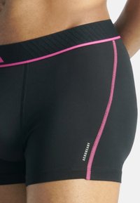 Shorts sportivi neri con una cintura testurizzata e dettagli rosa, caratterizzati da un logo e cuciture a contrasto lungo la cucitura laterale.