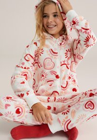 Mono de forro polar con capucha, con un patrón de corazones rosas y rojos y destellos de sol sobre un fondo blanco. Puños y bolsillos blancos acanalados.