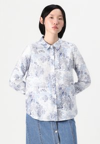 Cămașă cu butoni dintr-o țesătură ușoară, cu un model floral albastru pe un fundal alb, având un guler clasic și mâneci lungi.