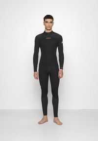 Mutino nero con maniche lunghe e gambe lunghe. Presenta una texture liscia, un design aderente e pannelli neri a contrasto sulle cosce.
