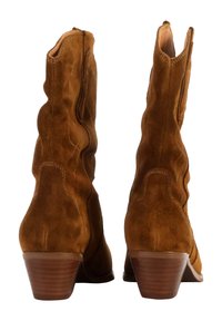 Botas de tobillo de ante marrón con diseño ondulado, cremallera lateral y tacón apilado. Presenta costuras decorativas y un forro interior suave.