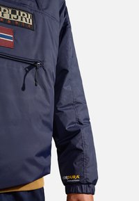 Marinblå nylonjacket med dragkedja och en framficka, som har en patch och Cordura®-logotyp på ärmen, elastiska ärmslut och ribbad nederkant.