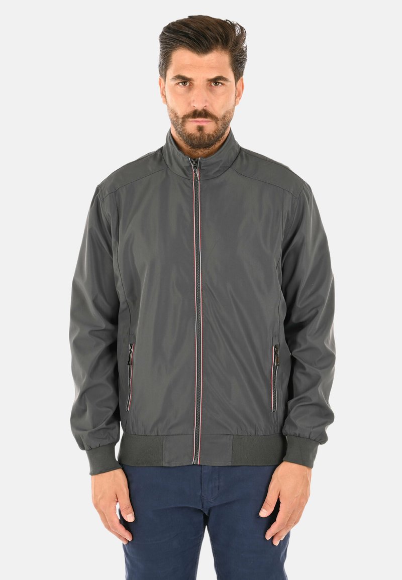 Giacca bomber grigia in materiale leggero, con colletto alto, zip frontale, tasche laterali e accenti a strisce in contrasto.