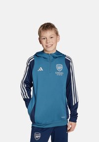 Teal sportieve hoodie met marineblauwe accenten, met een rits aan de voorkant, capuchon, gestreepte mouwen en het Arsenal-logo. Gemaakt van vochtafvoerende stof.