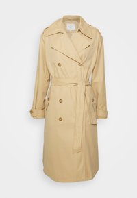 Trench-coat beige croisé avec large col, poignets boutonnés, deux poches devant et ceinture en tissu assorti nouée à la taille.