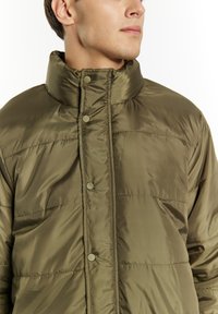 Giubbotto imbottito verde oliva con colletto alto, caratterizzato da bottoni a pressione e cuciture orizzontali trapuntate, realizzato in tessuto lucido e leggero.