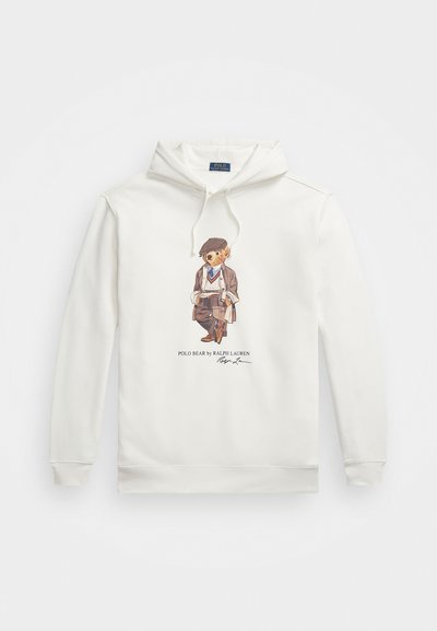 Vit hoodie med framsidan tryckt med en björn som bär en platt hatt, kavaj, tröja och scarf, som håller ett rullat papper, med texten Polo Bear av Ralph Lauren.