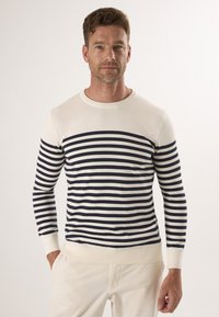 Sweter w paski w kolorze kremowym i granatowym, okrągły dekolt, długie rękawy, prążkowane mankiety i dolna krawędź, miękka tekstura, dopasowany krój.