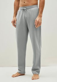 Pantalones de chándal grises hechos de una tela suave, con una cinturilla elástica con cordón, costuras laterales y un corte relajado. Sin bolsillos.